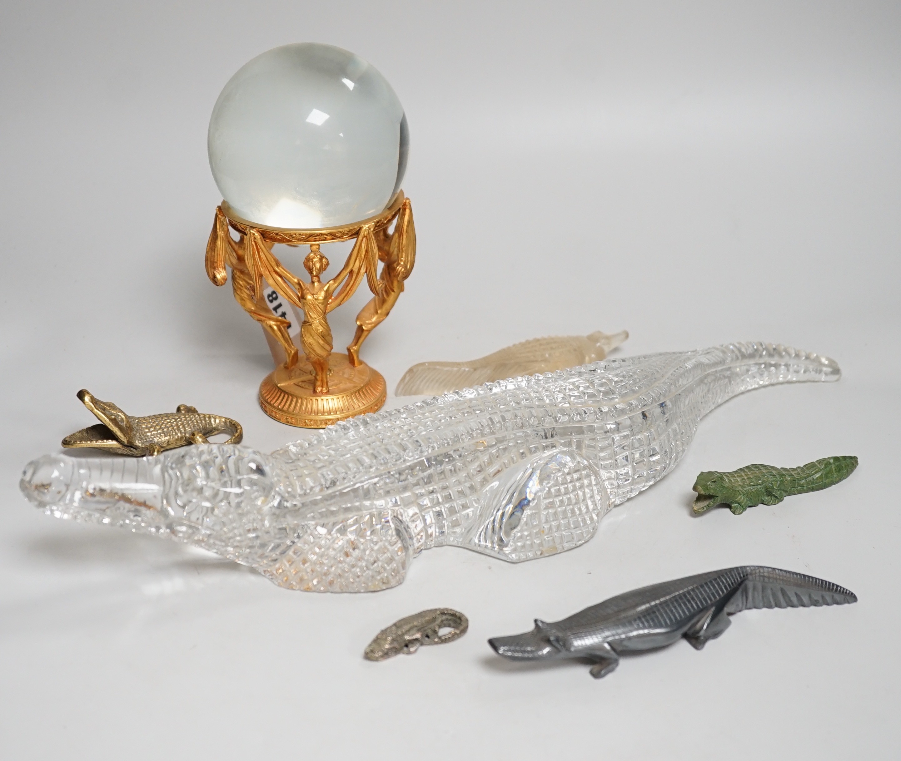 A crystal ball on gilt metal stand, 19cm tall, together with a hermatite crocodile, a jade type crocodile and four other crocodiles